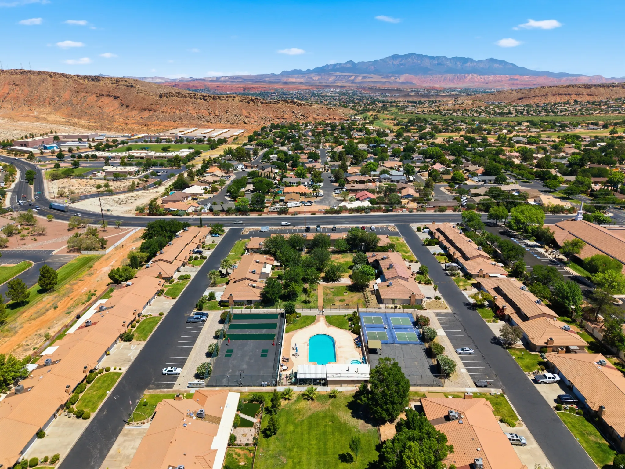 Aerial perspective highlighting a community with a central swimming pool and multiple tennis courts