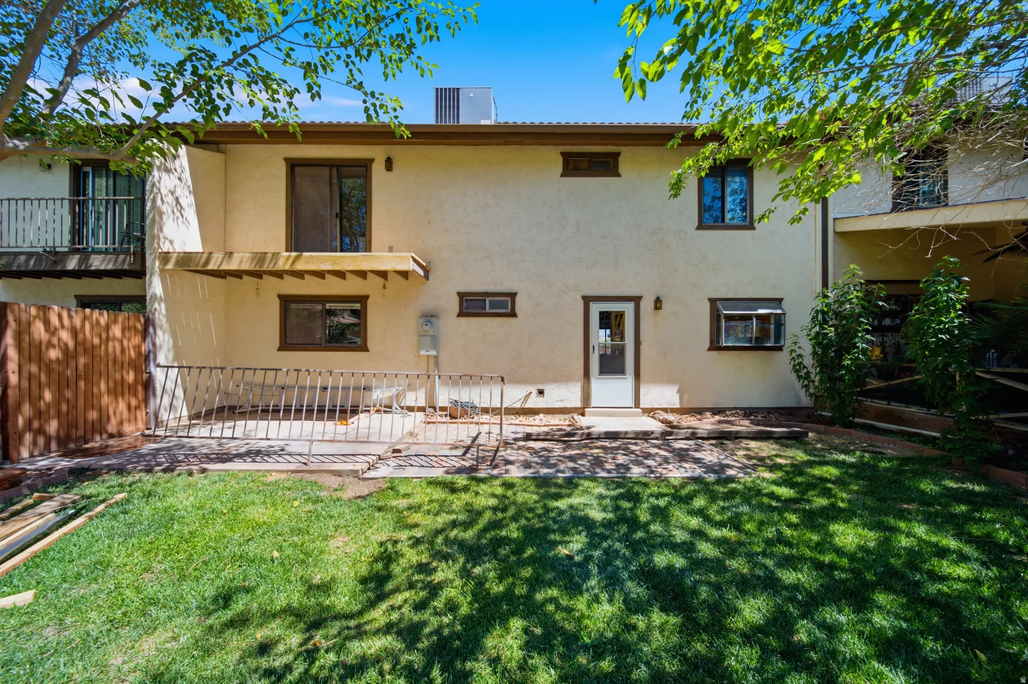 Rear exterior featuring a stucco facade, ground-level patio, and upper-level balcony