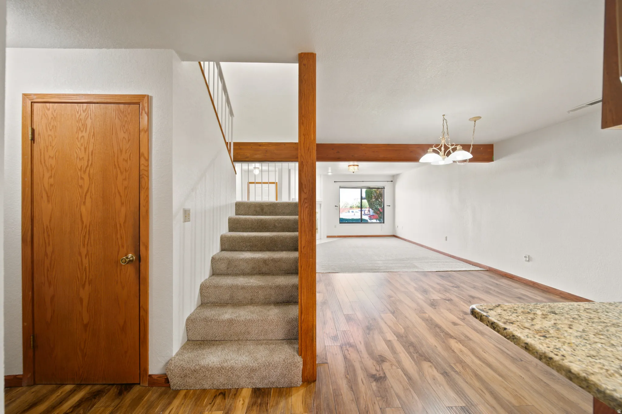 Interior entryway featuring wood-finish flooring, a carpeted staircase, and a wood-paneled door