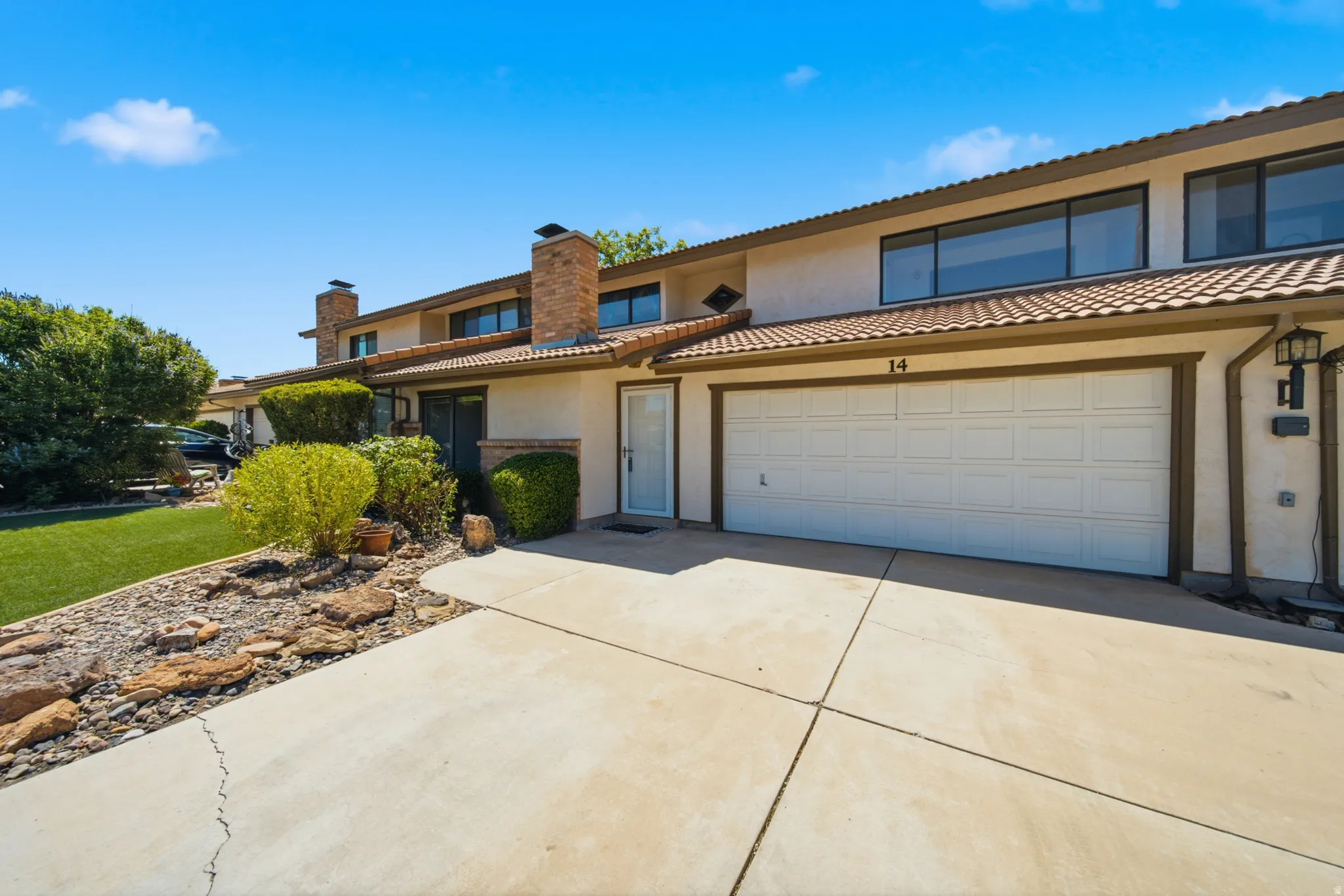 Single-family residence featuring a two-car garage with a panel door, stucco exterior, and a tile roof