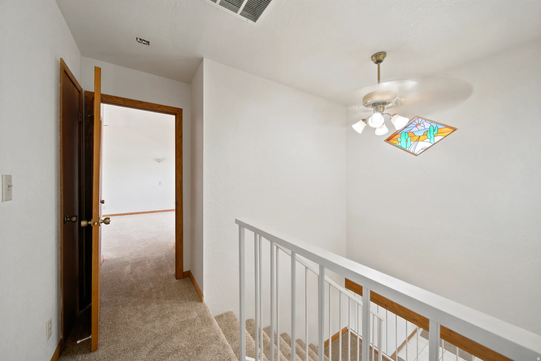 Carpeted staircase with white railing leading to a landing with a wood-framed doorway