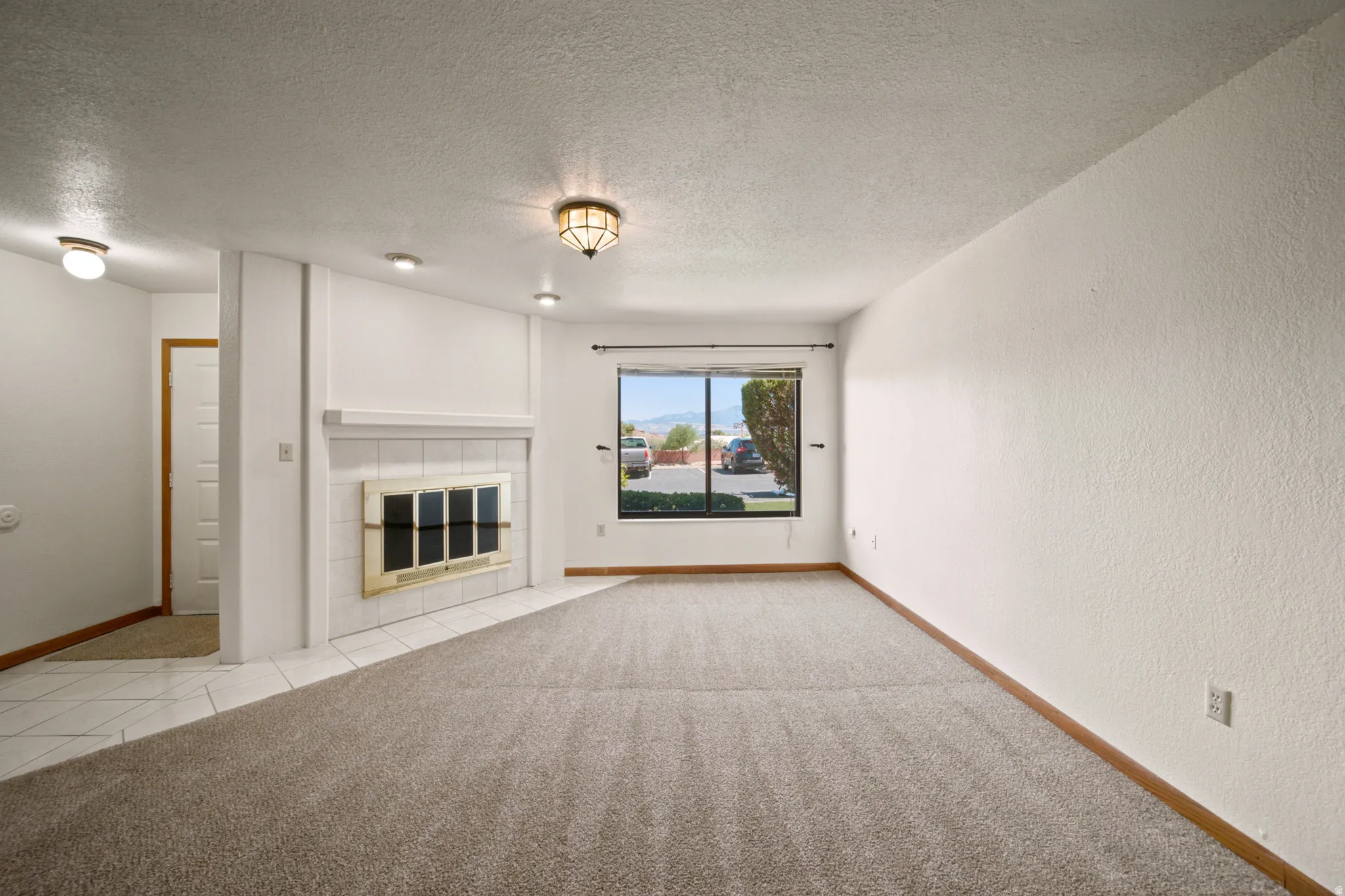 Living area featuring a fireplace with a white tile hearth, recessed lighting, and a front-facing window
