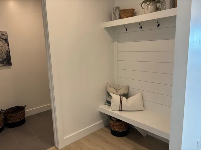 Built-in entryway bench with shiplap backing, integrated upper shelf, and three coat hooks