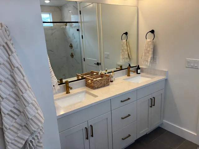 Bathroom featuring a double vanity with light-toned countertops, undermount sinks, and brass-finish faucets