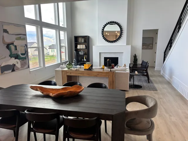 Spacious open-concept living area featuring high ceilings, light wood-finish flooring, and a contemporary fireplace with a white surround