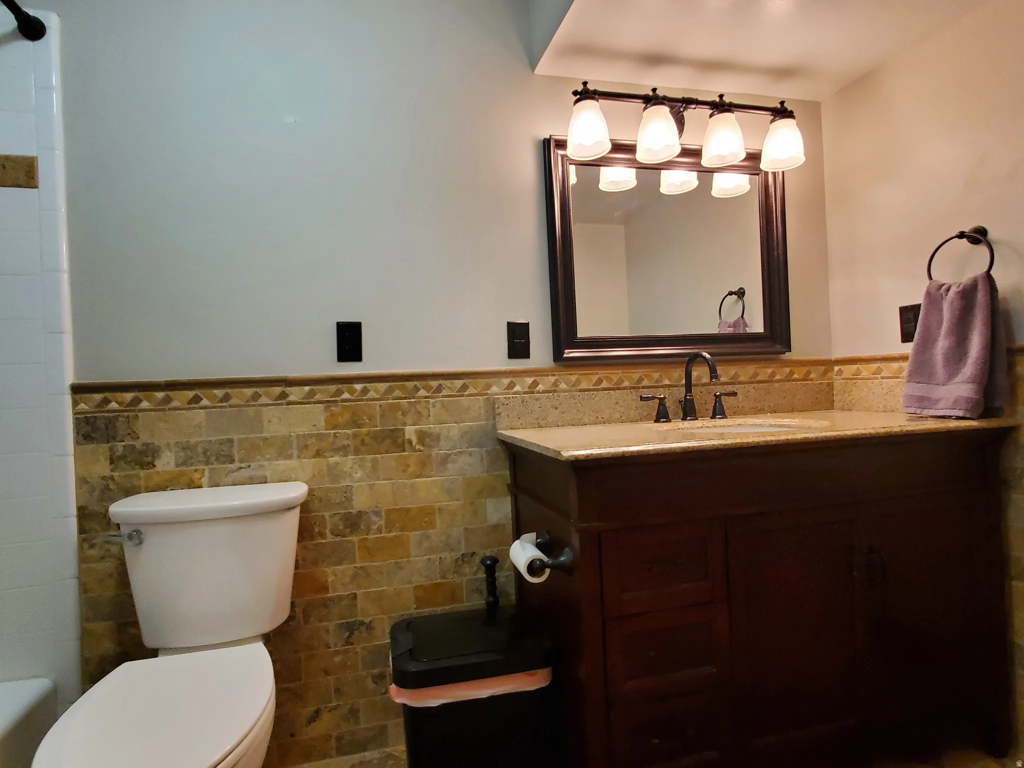 Bathroom featuring a rich wood-tone vanity, a light-toned countertop, and an undermount sink with a dark-finished faucet