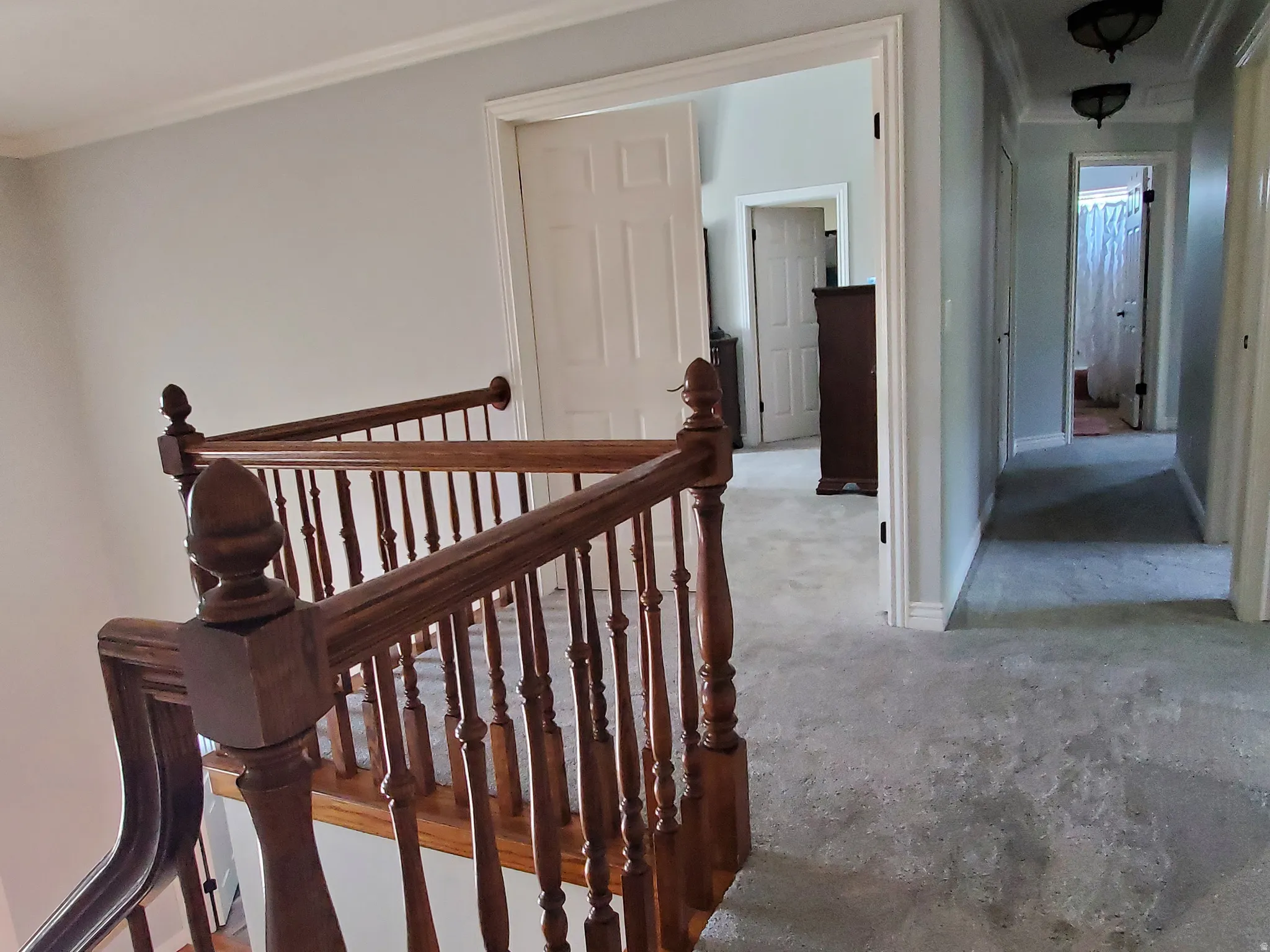 Wood-finish staircase with turned spindles and a carpeted upper landing