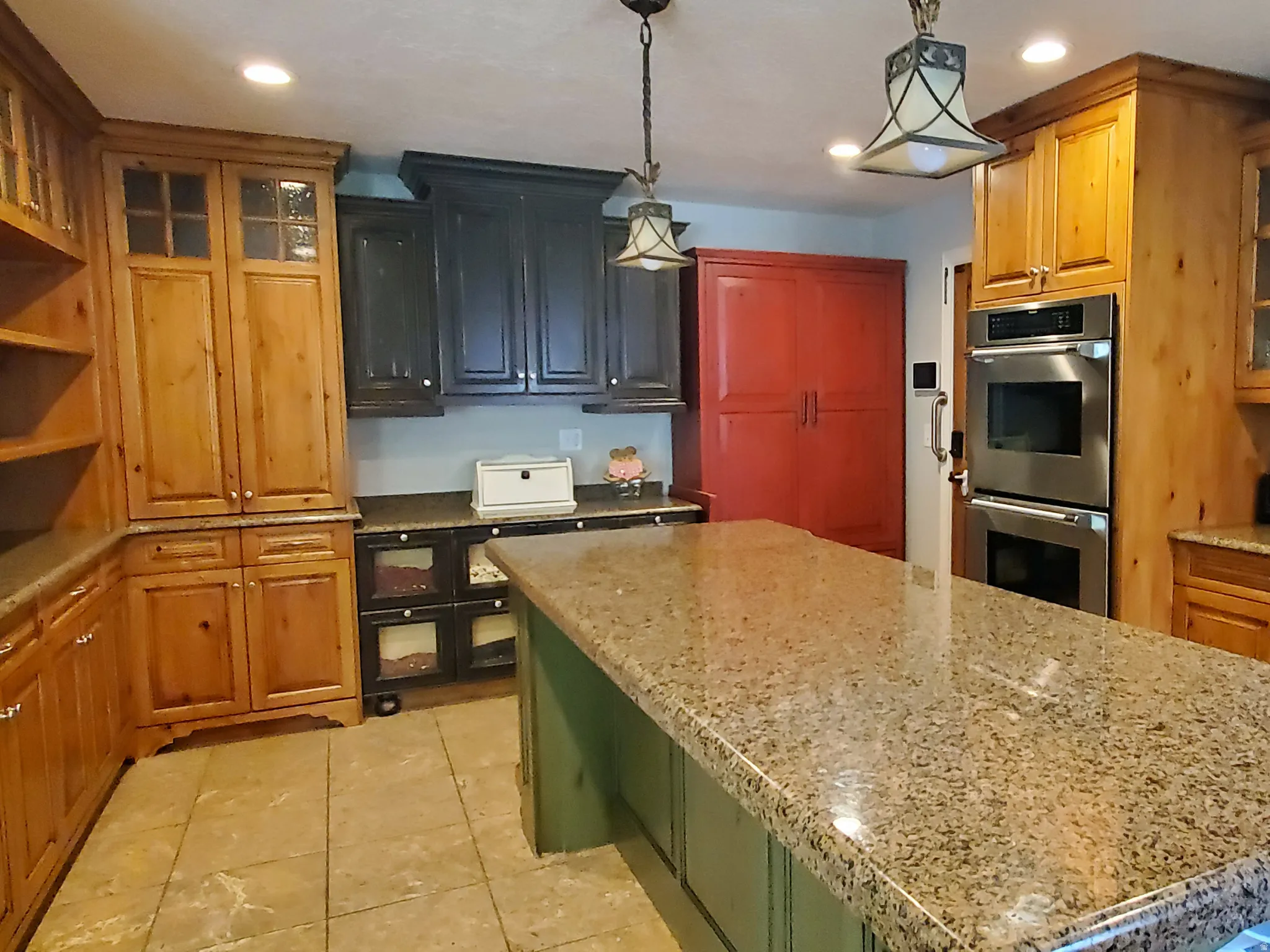 Kitchen featuring a large island with a stone countertop, built-in double ovens, recessed lighting, and tile flooring
