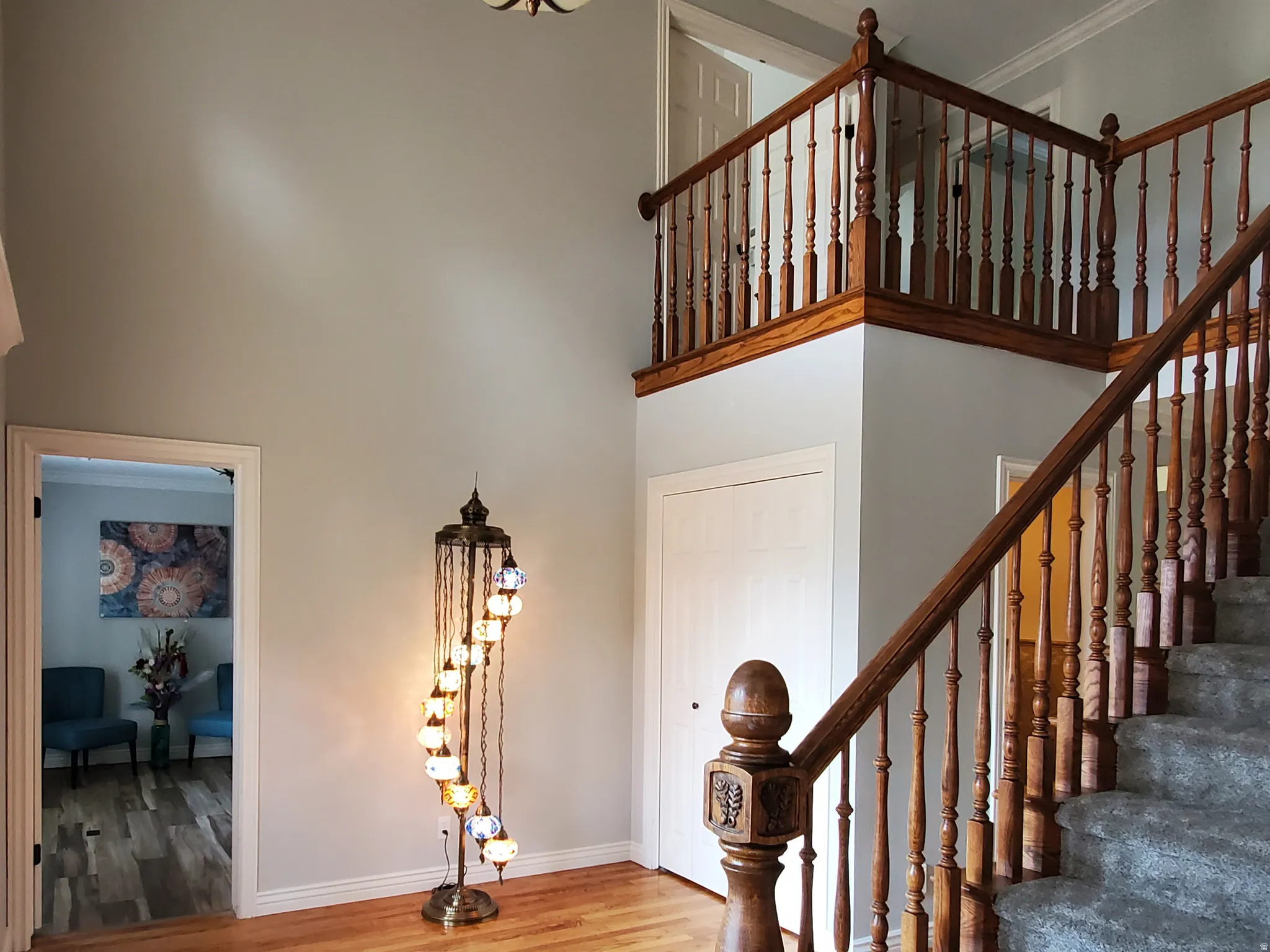 Two-story entry featuring wood-finish flooring, a grand staircase with carved wood newel posts and balusters, and a carpeted stairway