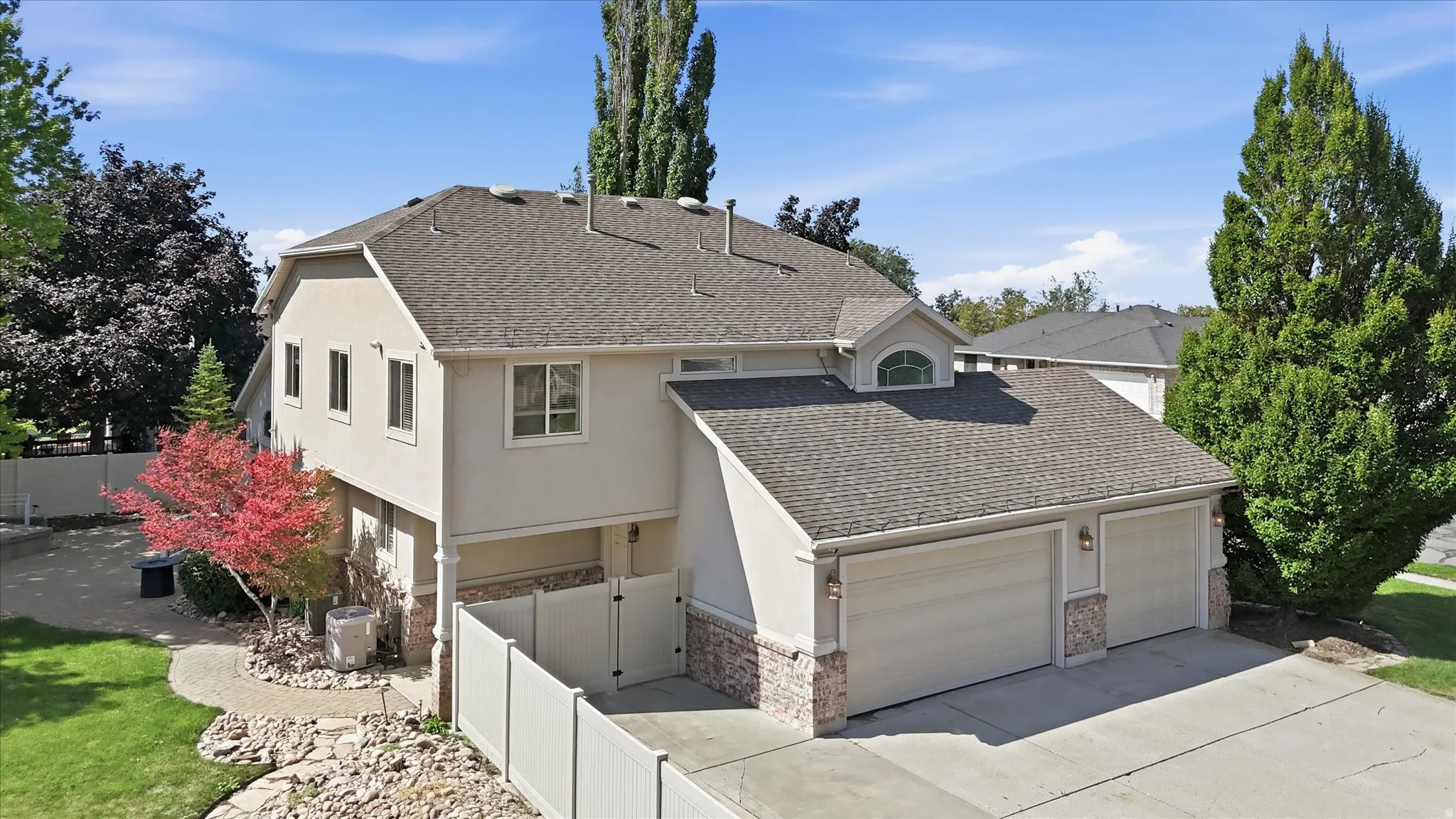 Stucco exterior residence featuring a two-car garage with stone accents, a dormer window, and a gabled roof