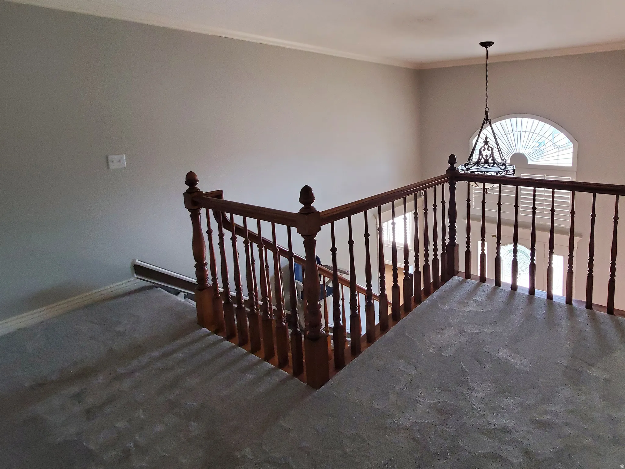Upper-level landing featuring hardwood banisters, gray carpeting, and crown molding