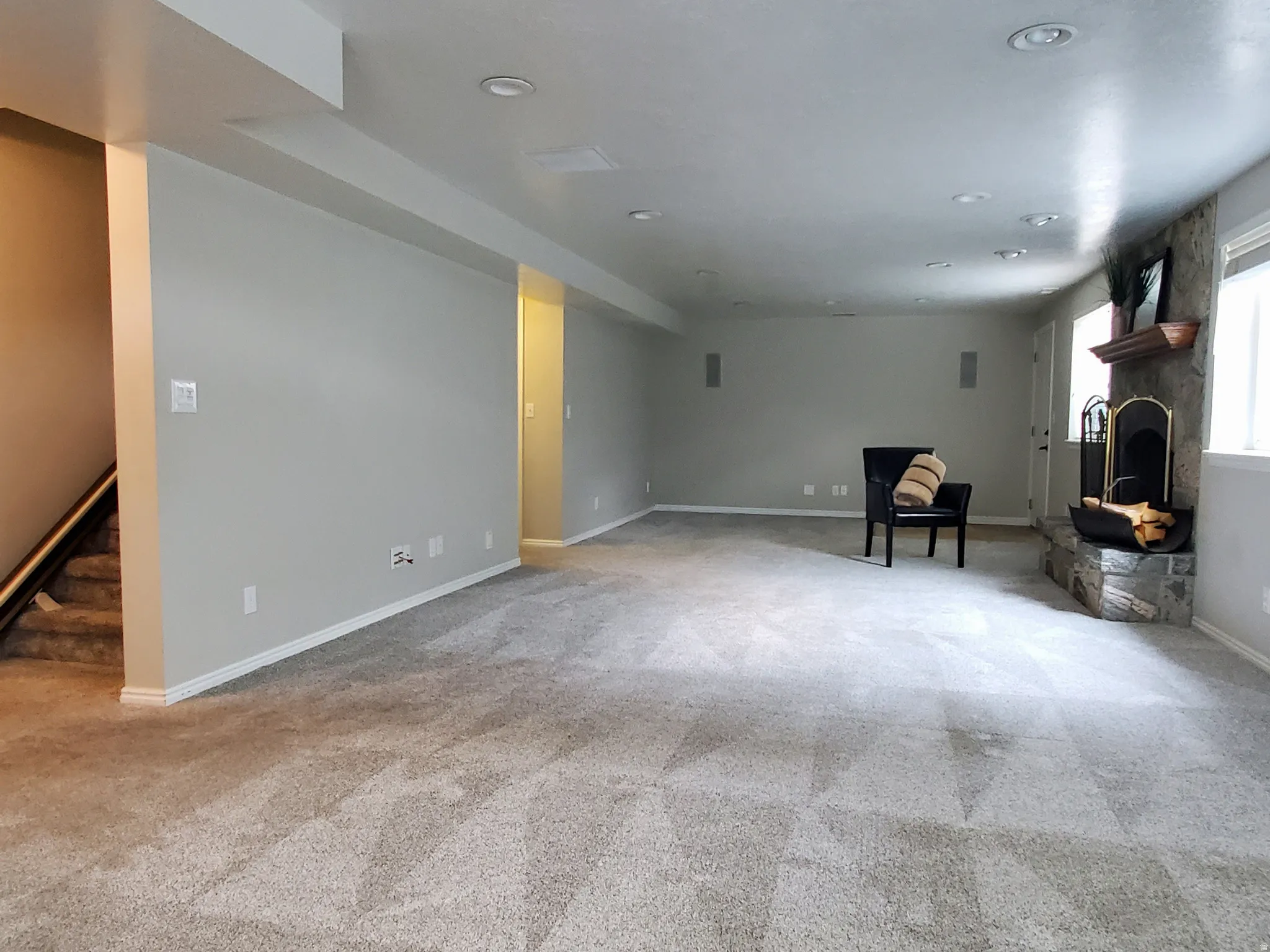 Expansive room featuring light gray walls, recessed lighting, and soft gray carpeting