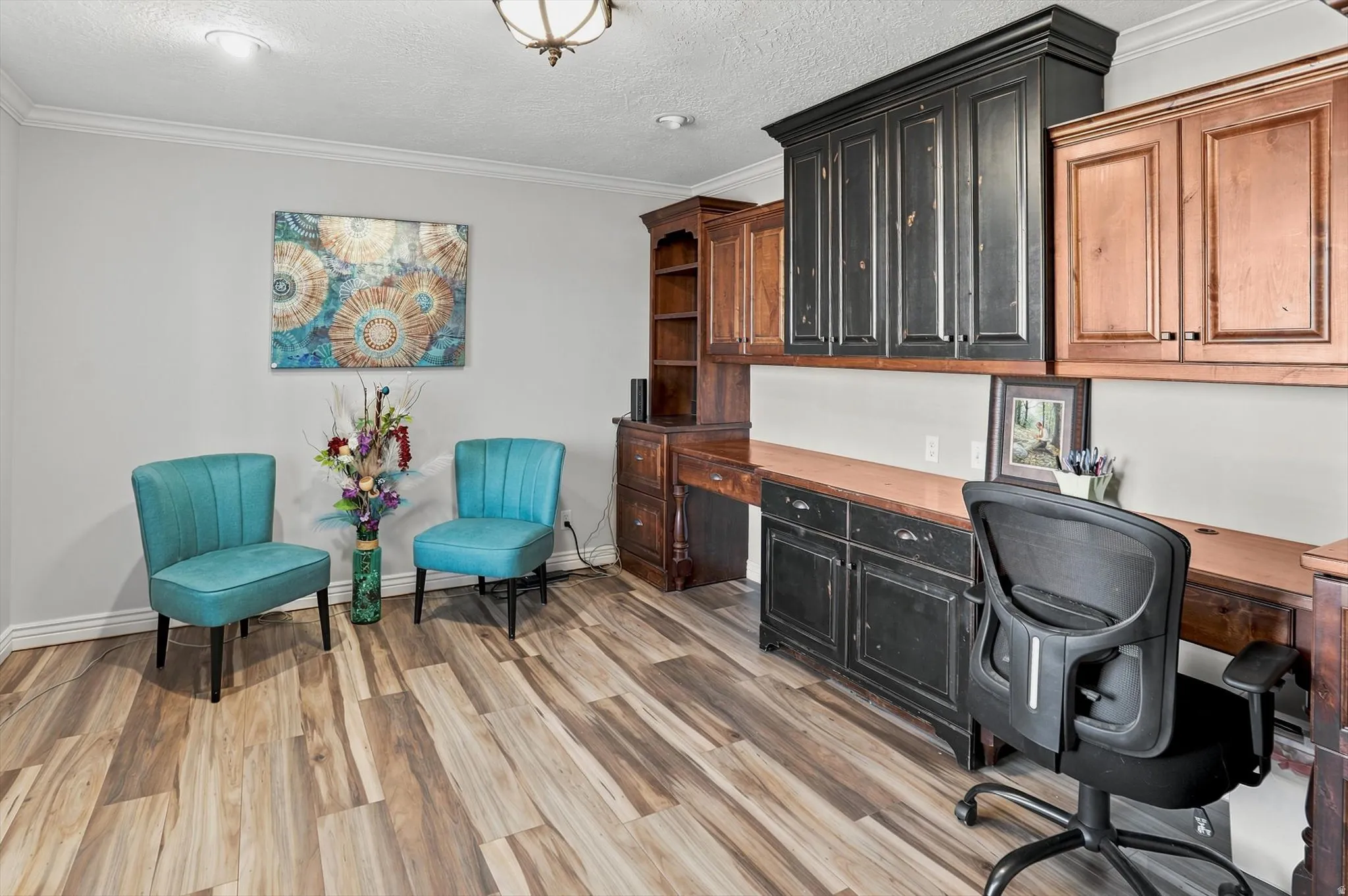Dedicated workspace featuring extensive built-in cabinetry, wood-finish flooring, and crown molding