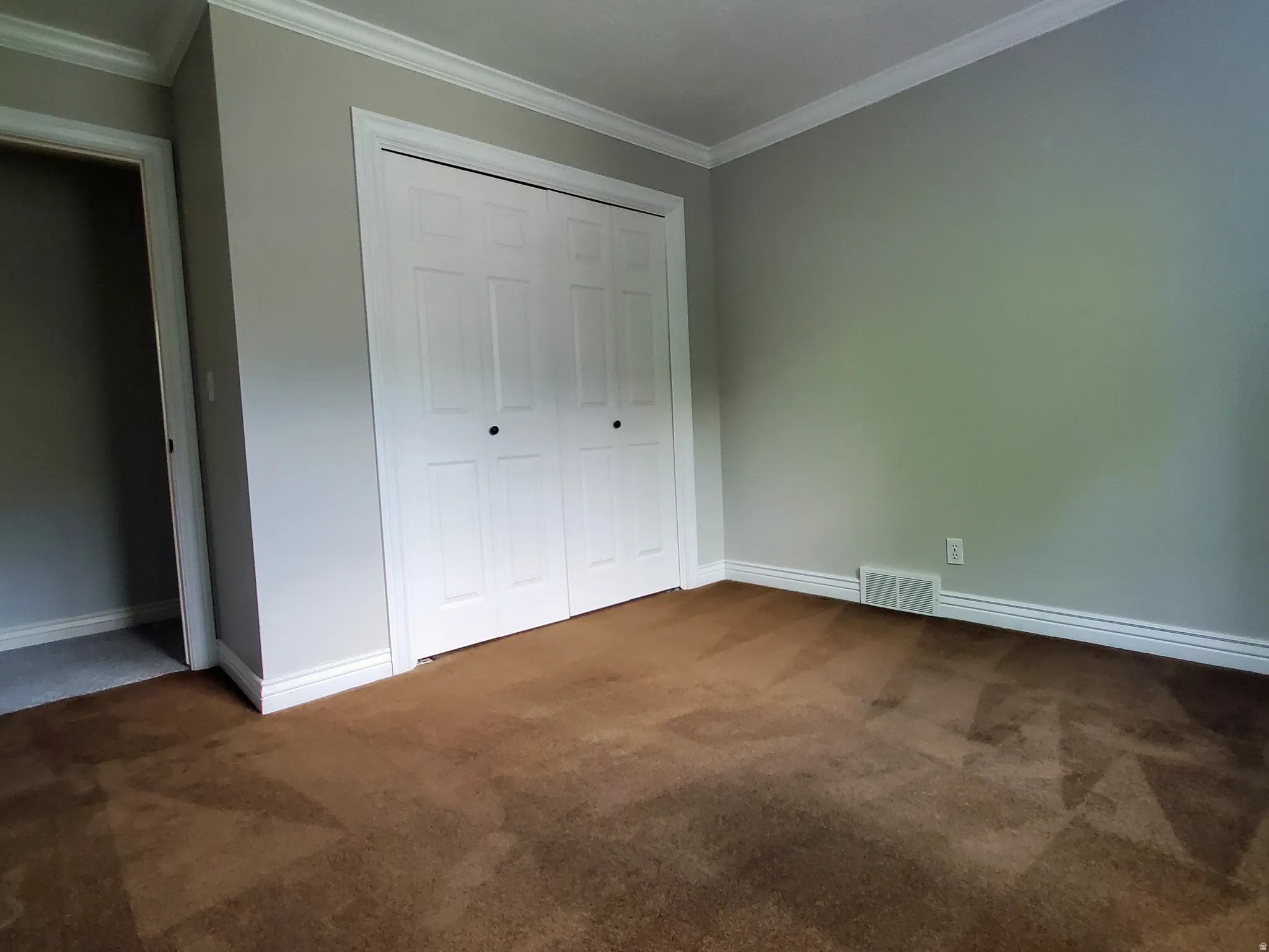 Room featuring neutral wall paint, white crown molding, and white baseboards
