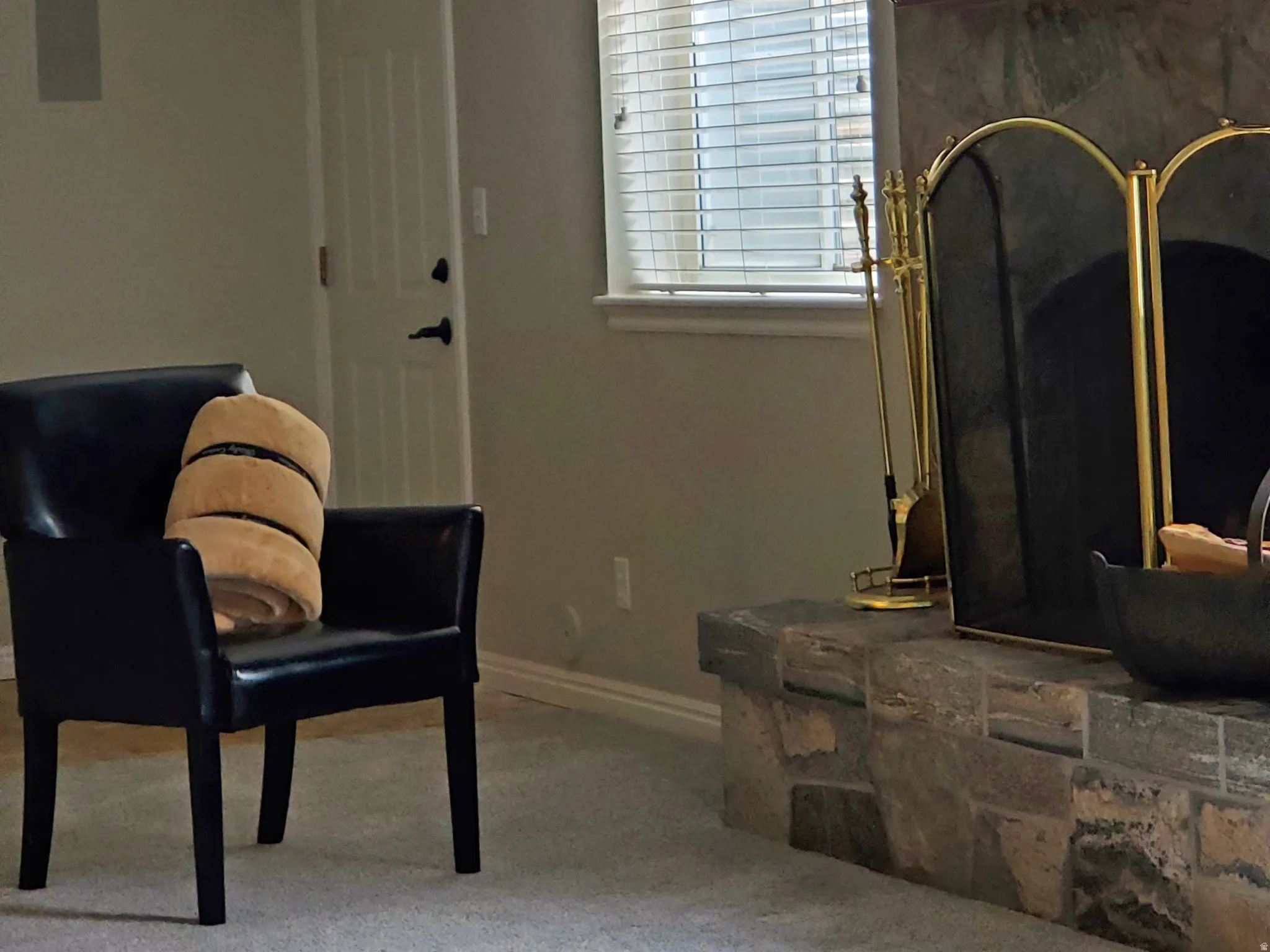 Stone-clad fireplace with a hearth and a window featuring horizontal blinds