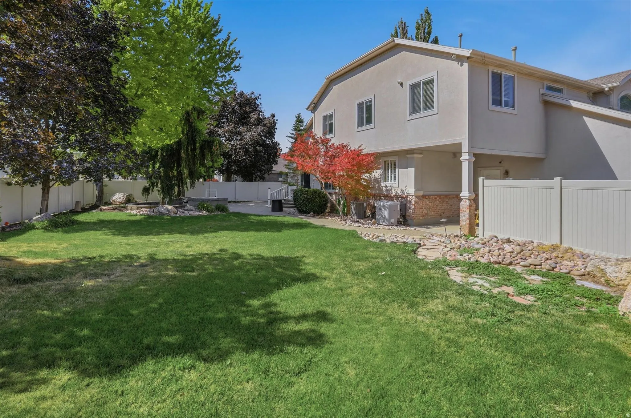 Expansive lawn area bordered by mature trees and a privacy fence