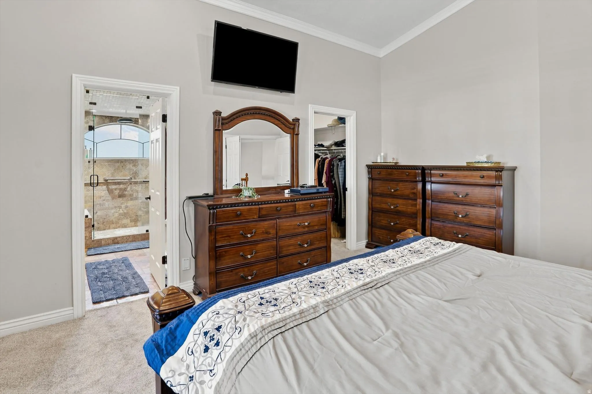 Carpeted bedroom featuring vaulted ceilings, crown molding, and direct access to a walk-in closet