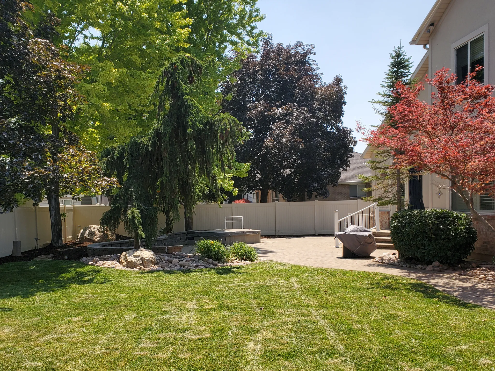 Expansive lawn featuring mature trees and a paver patio