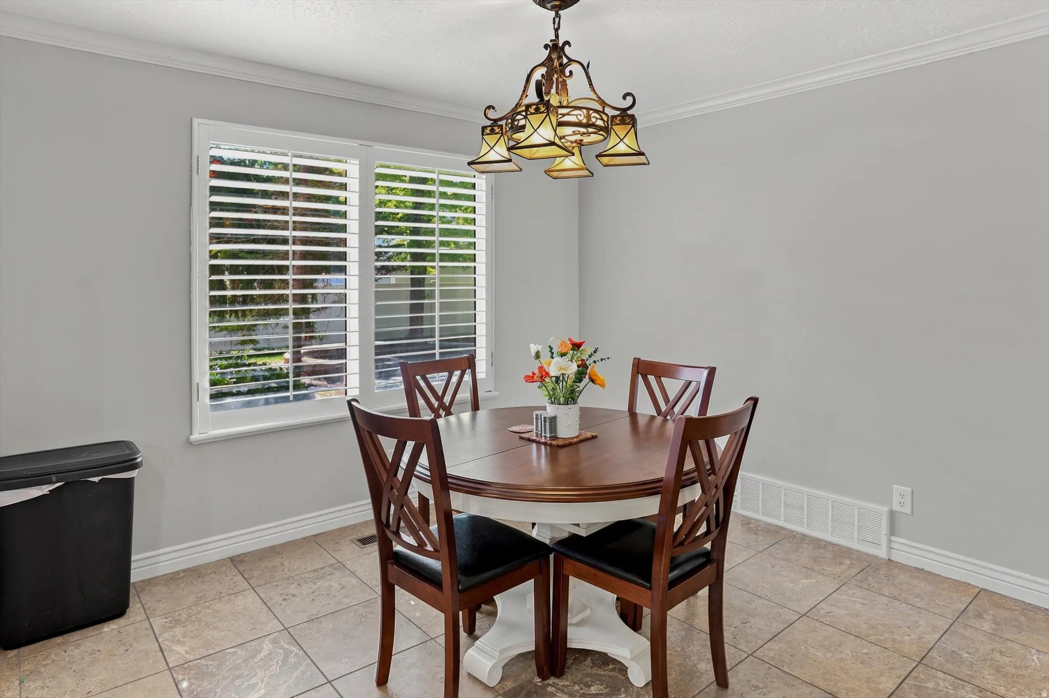 Dining space featuring tile flooring, crown molding, white baseboards, and a decorative chandelier