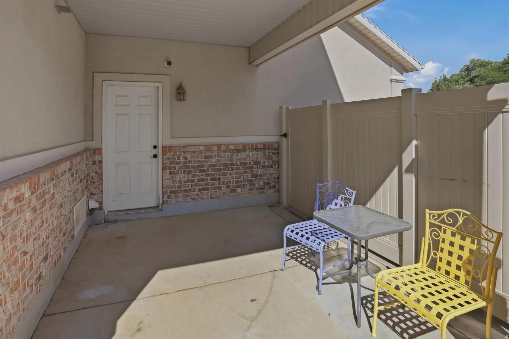 Private covered patio featuring a concrete slab and a brick wainscoting