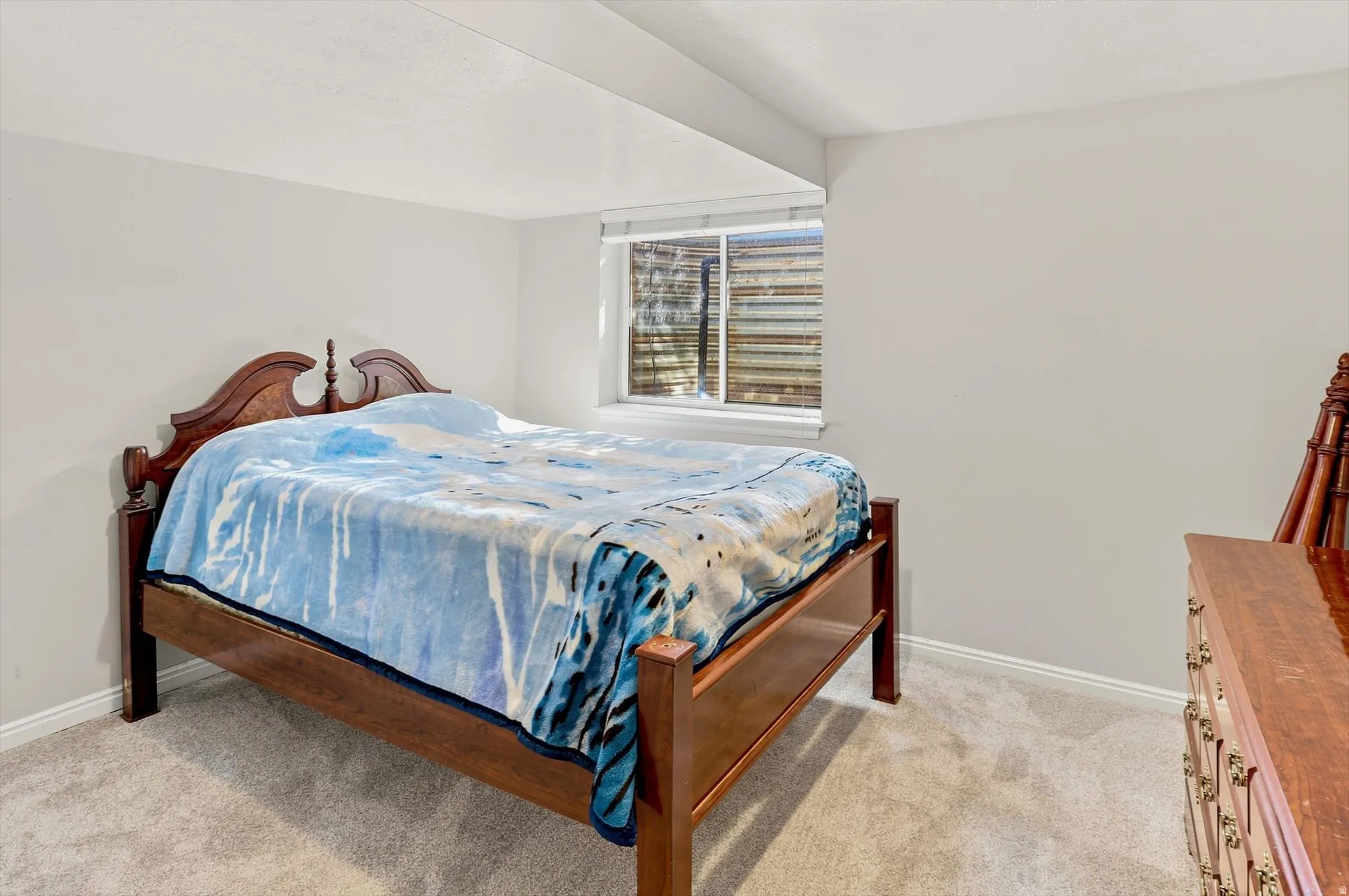Carpeted room featuring a single window with blinds, white walls, and white baseboards