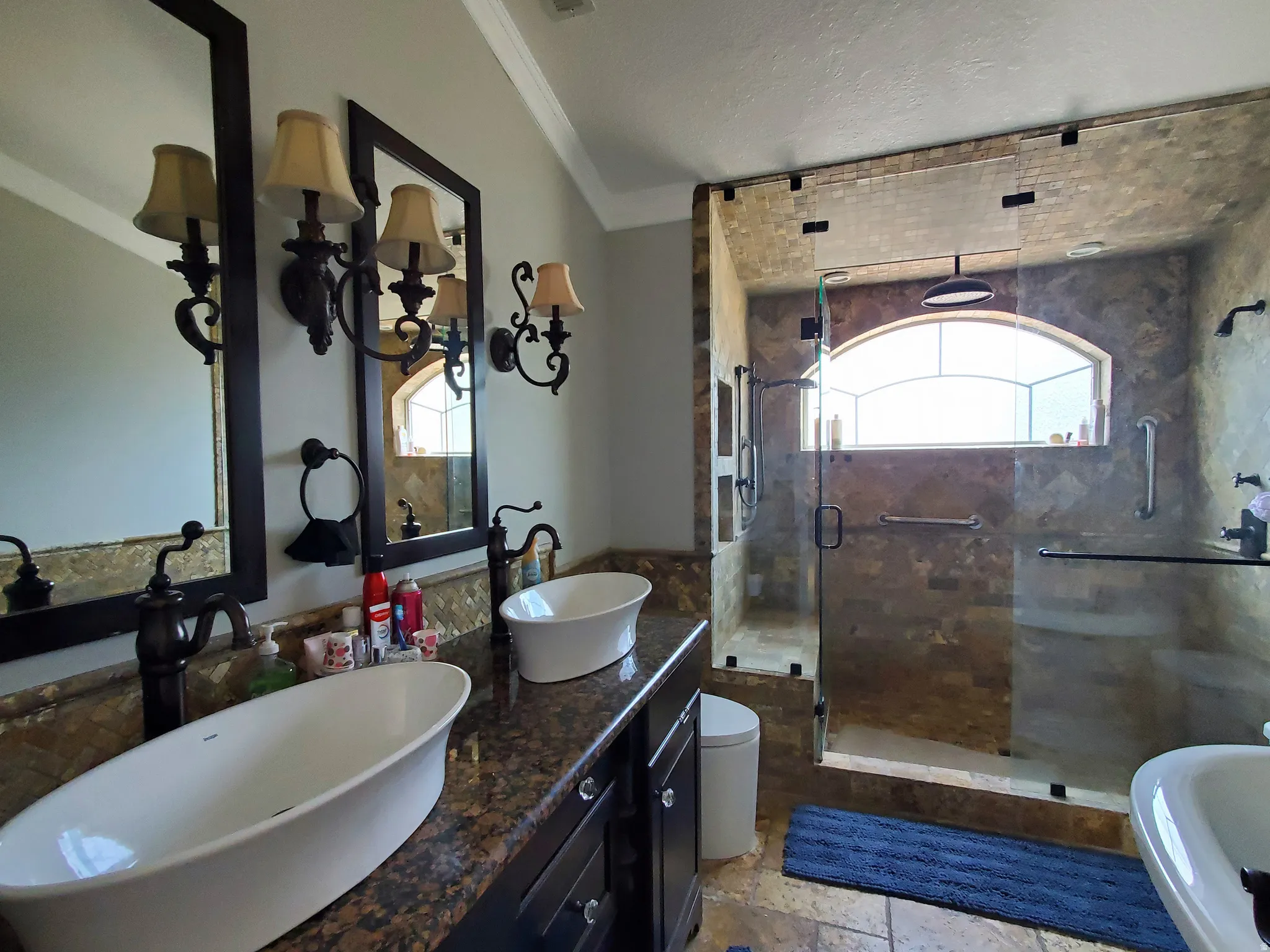 Bathroom featuring a spacious walk-in shower with stone-finish tile, an arched window, and a rain showerhead