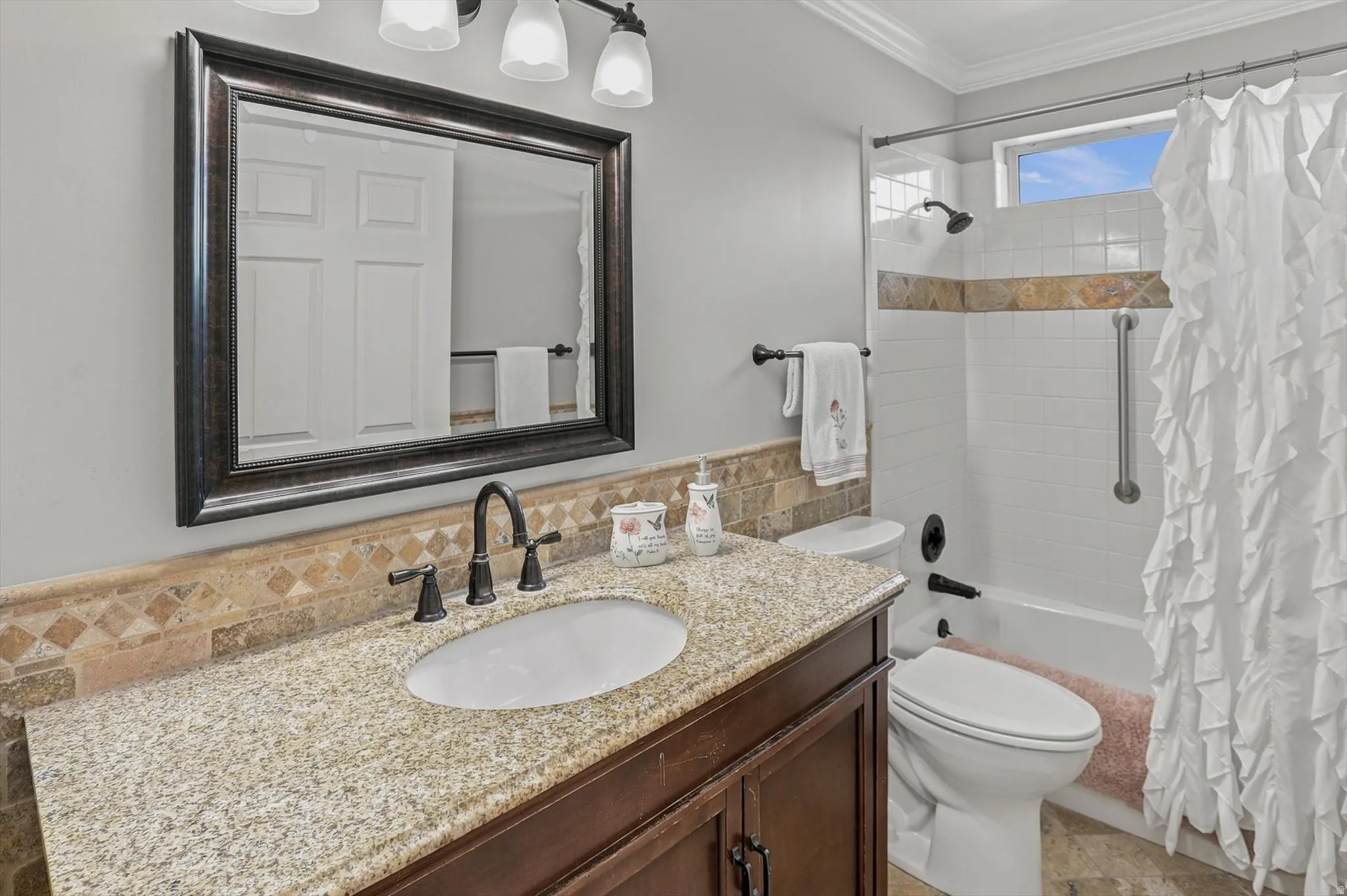 Spa-inspired bathroom featuring a framed vanity mirror, granite-topped double-sink vanity with dark wood cabinetry, and a matte black faucet