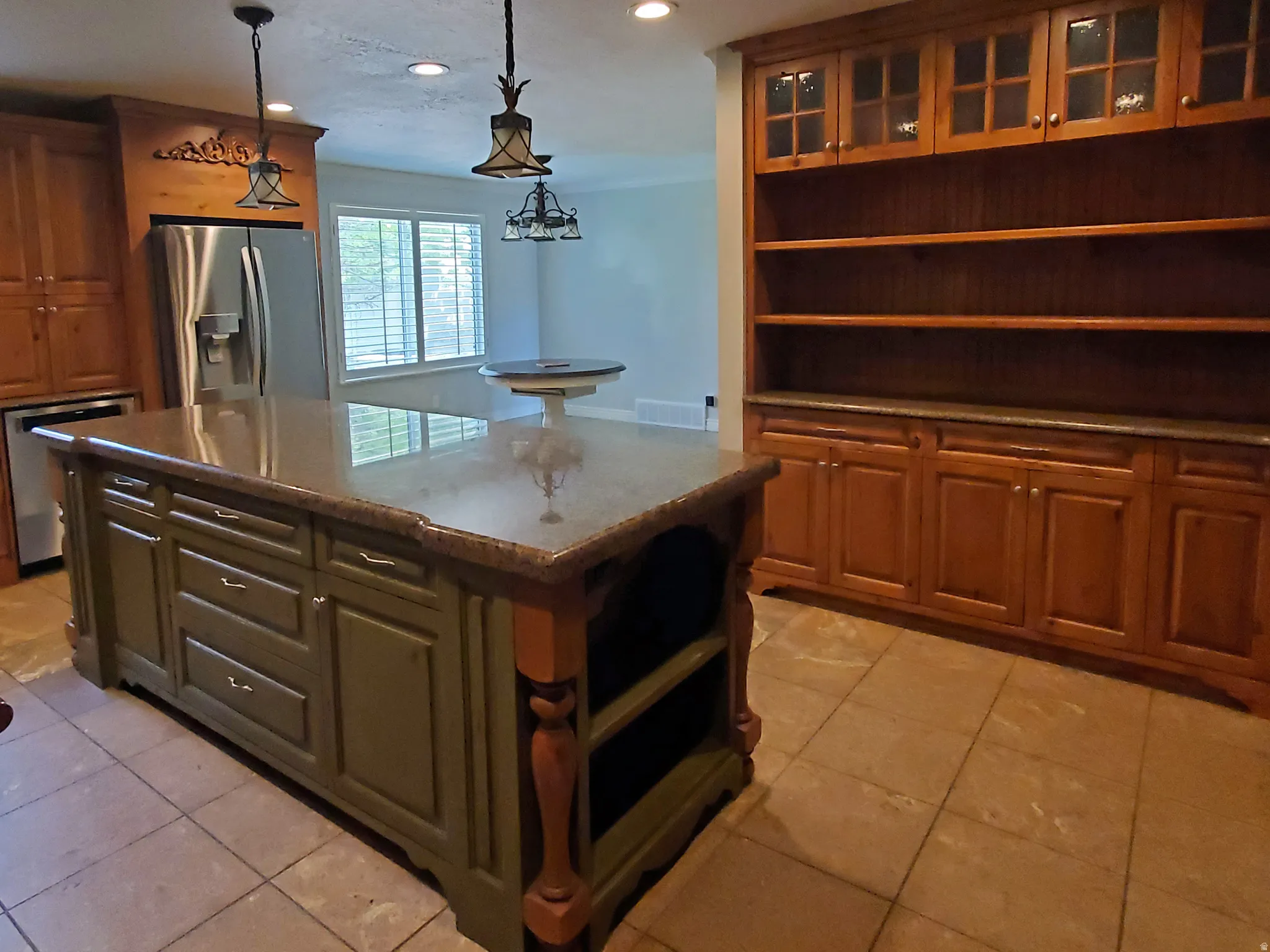 Spacious kitchen featuring a large central island with storage, stone countertops, and tile flooring