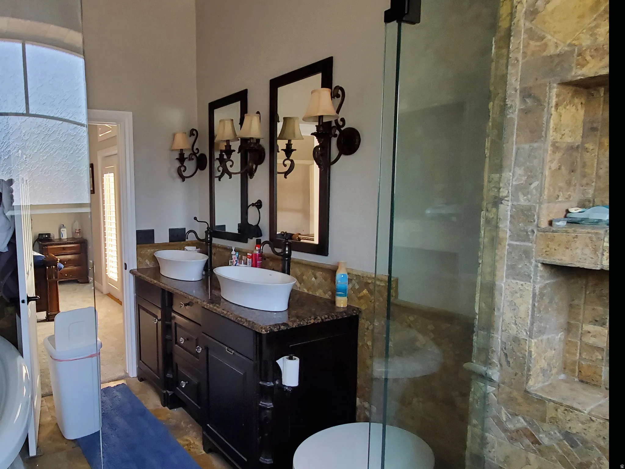 Double vanity featuring vessel sinks, dark wood cabinetry, and a granite-finish countertop