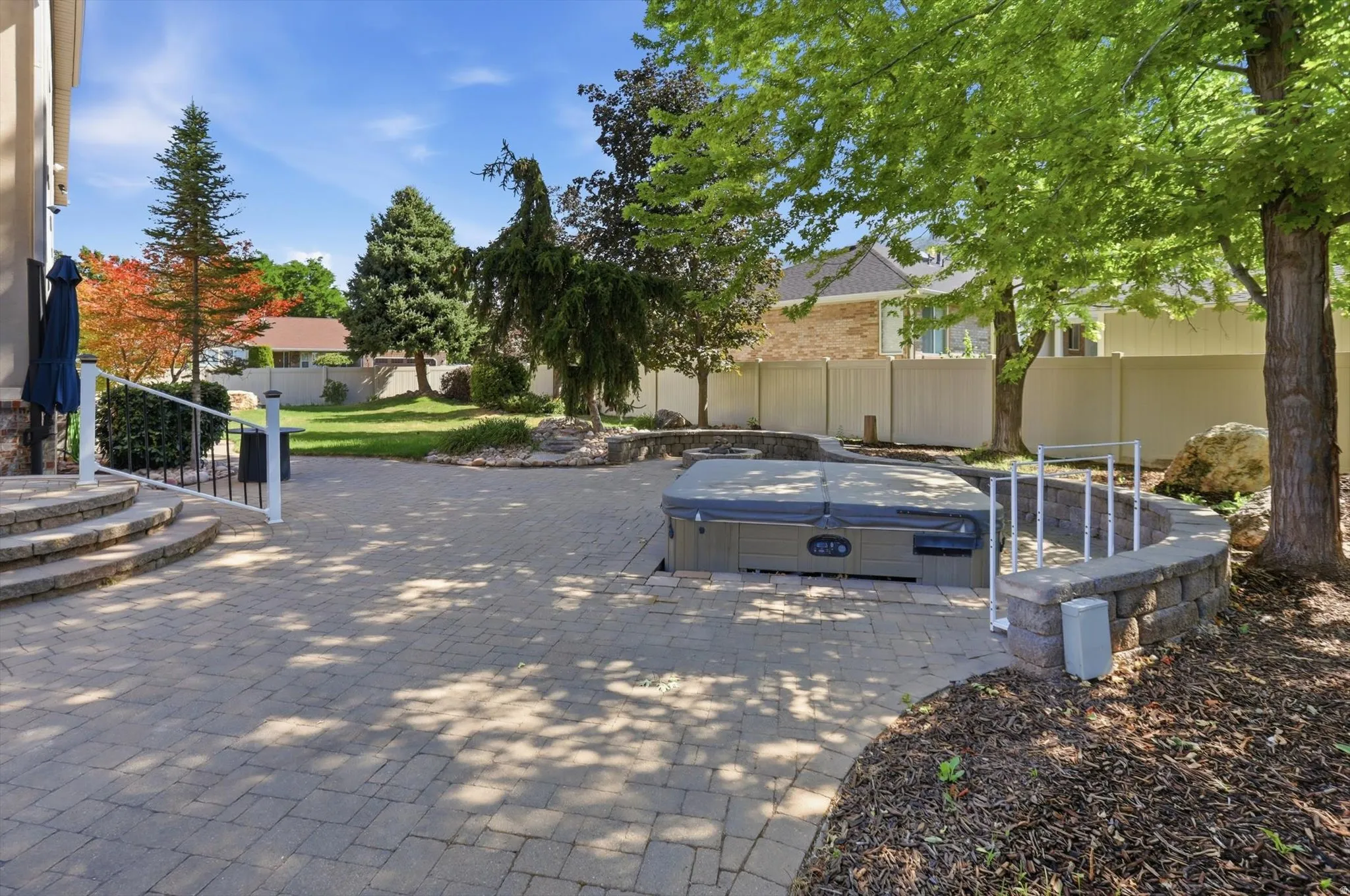 Expansive paver patio featuring a built-in hot tub