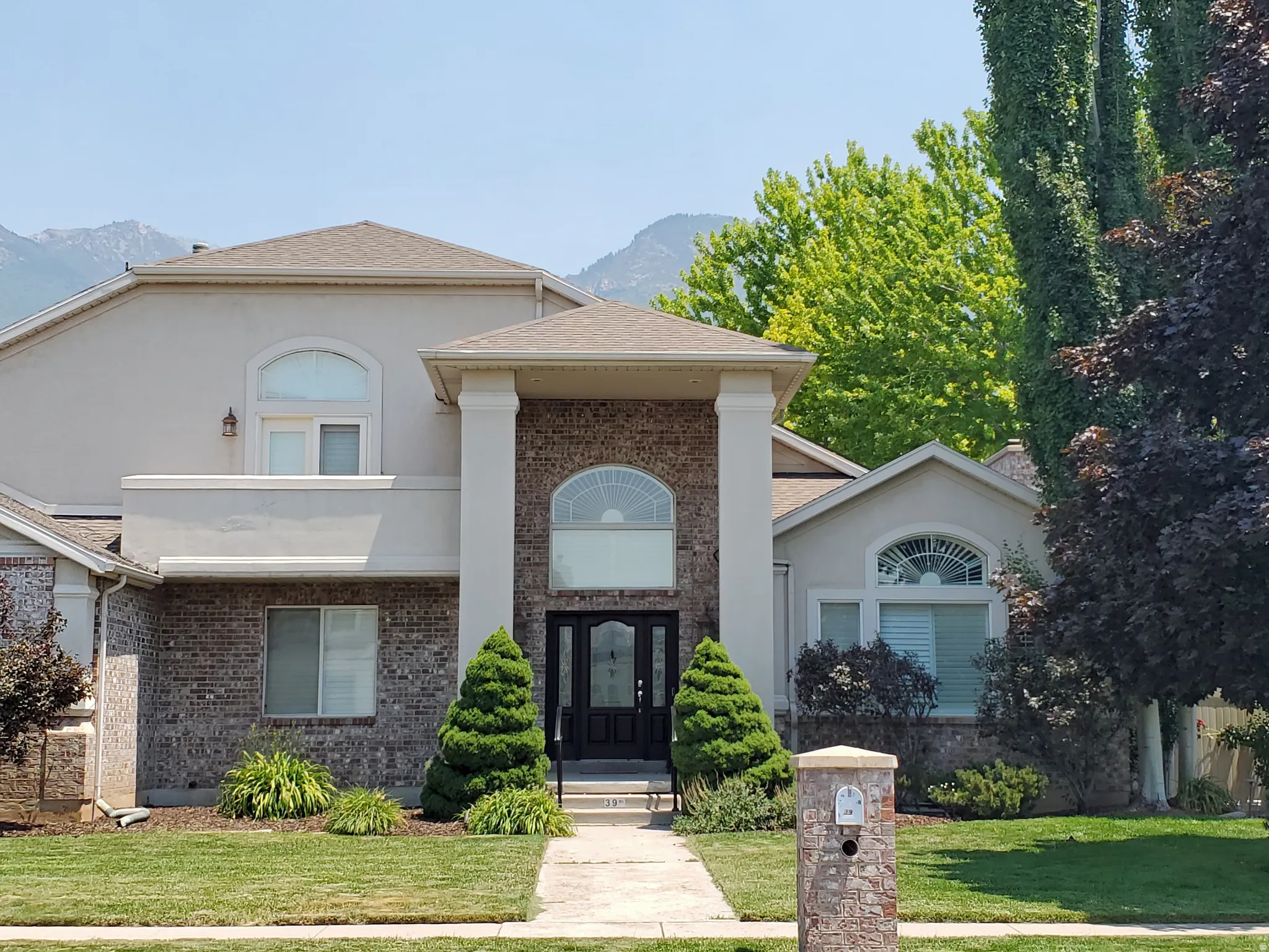 Stucco and brick facade with prominent architectural columns framing the double entry doors