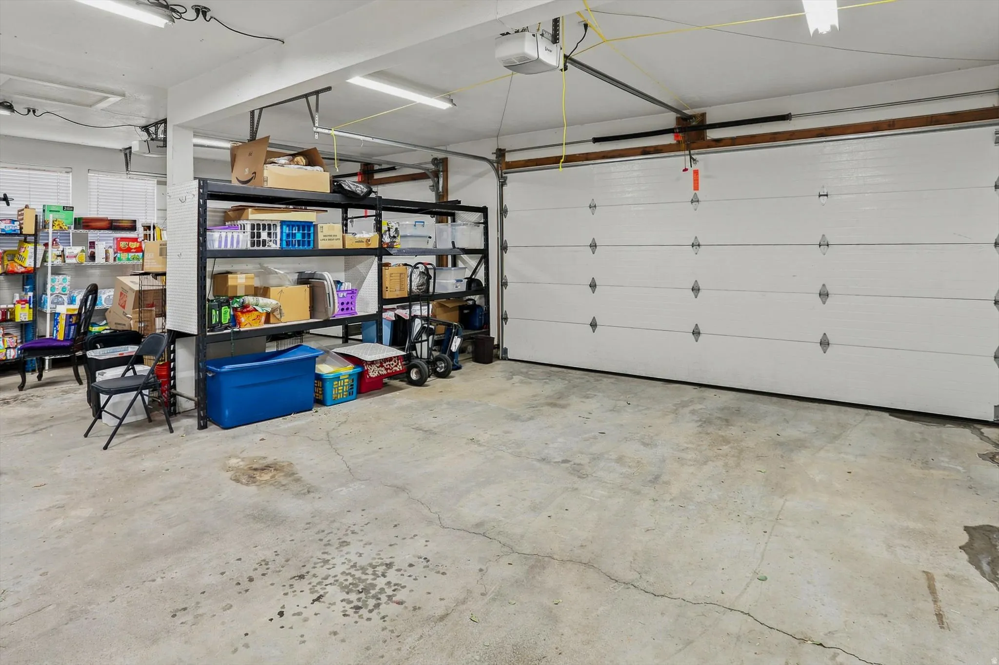 Spacious garage featuring a sectional garage door, concrete flooring, fluorescent lighting, and built-in shelving