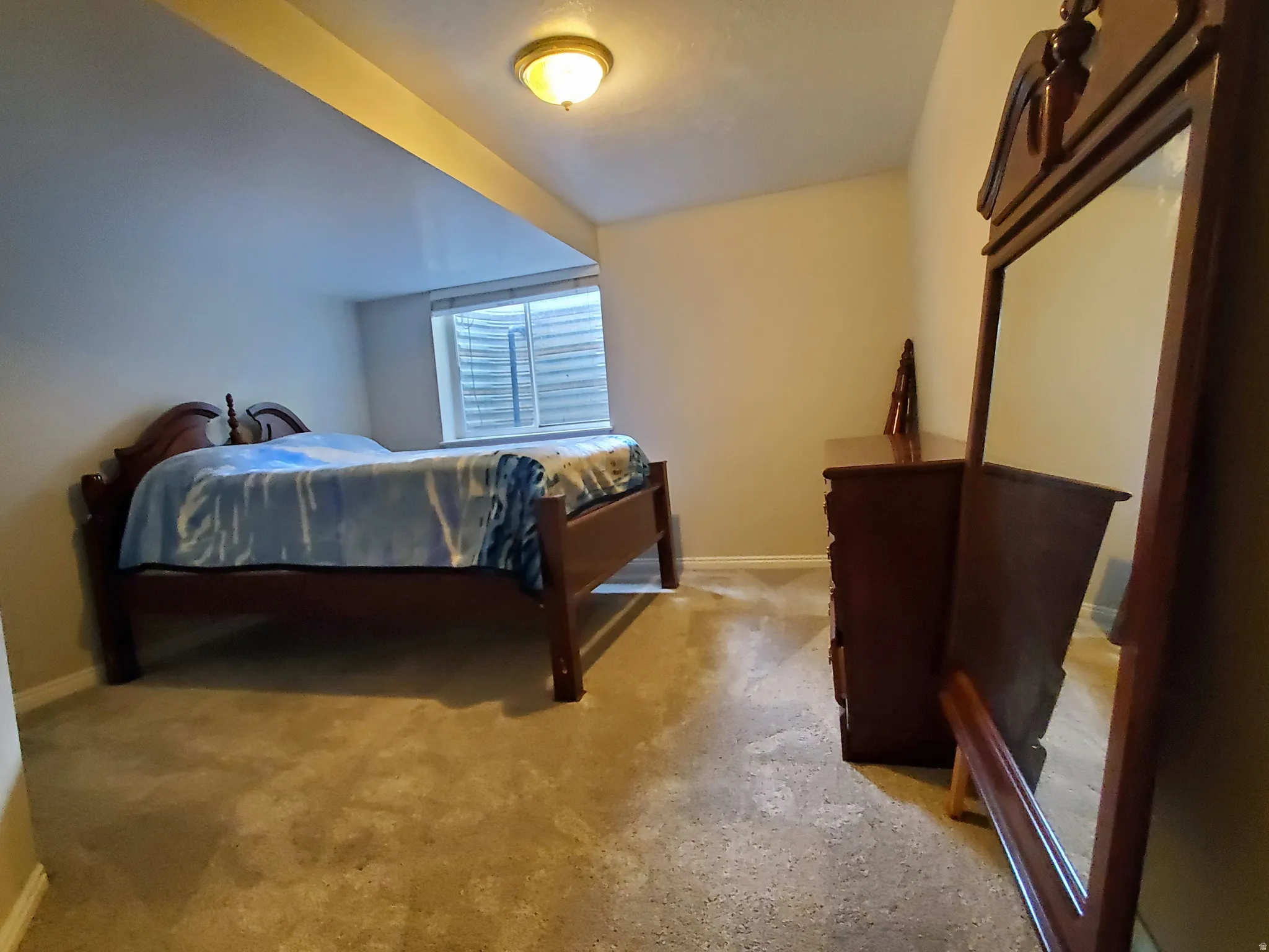 Carpeted room featuring a single window with horizontal blinds, a neutral wall color, and a ceiling-mounted light fixture