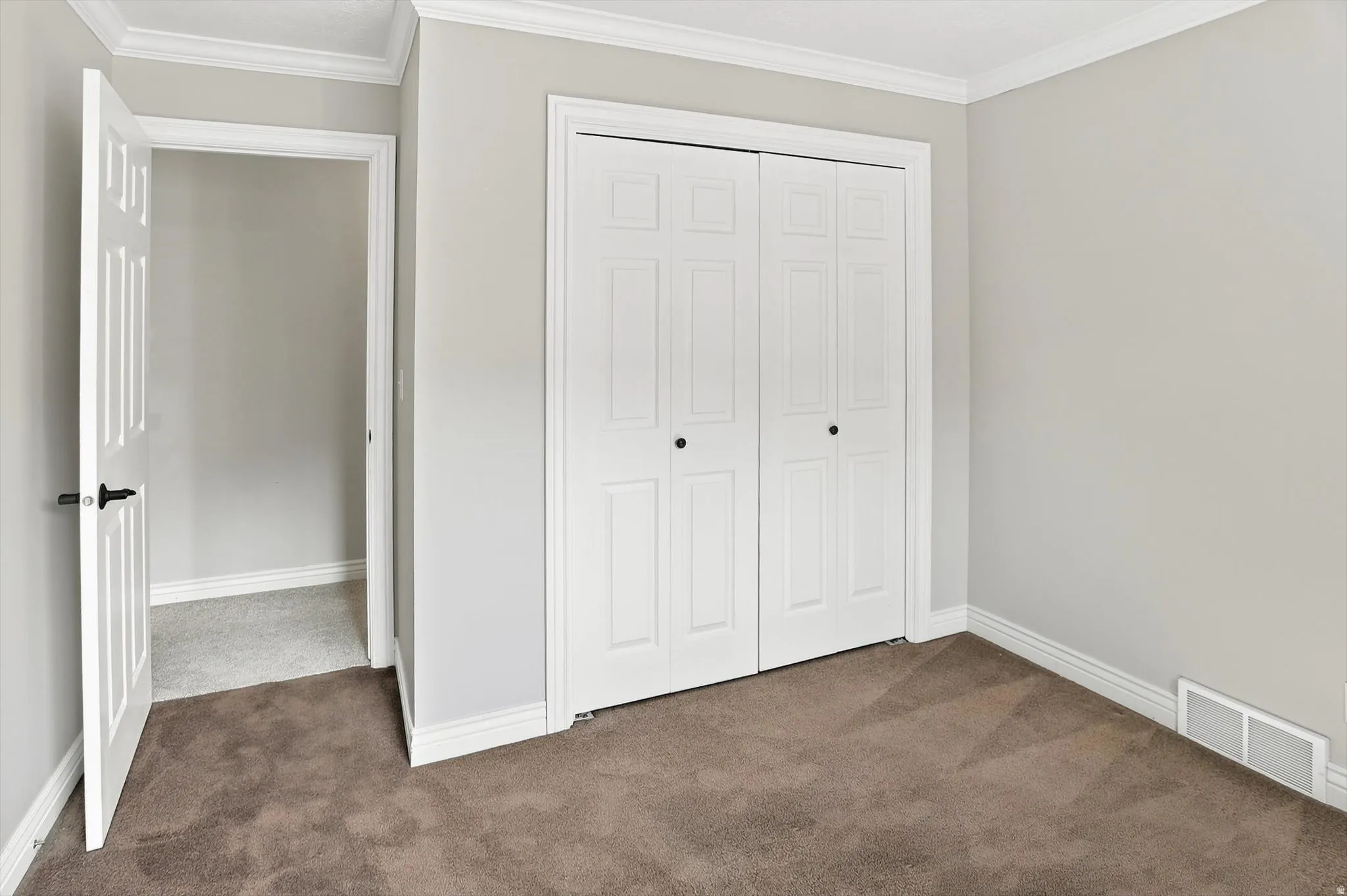 Room featuring neutral wall paint, white crown molding, and white baseboards