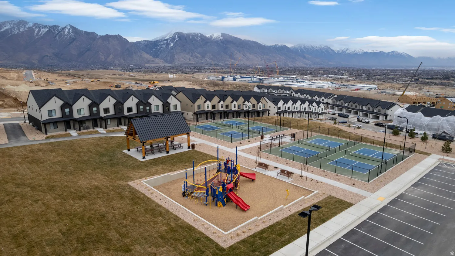 Community amenities featuring multiple pickleball courts, a covered pavilion with picnic tables, and a playground area