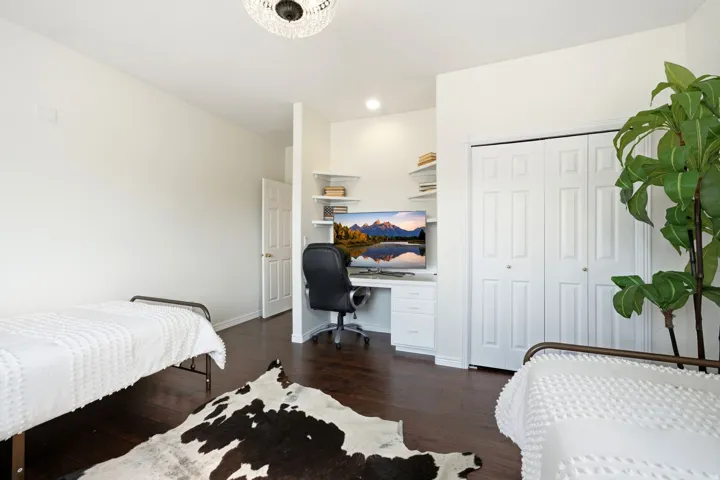Built-in desk area with shelving, dark wood-finish flooring, white bifold closet doors, recessed lighting, and a decorative ceiling fixture