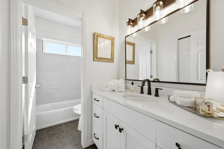 Bathroom featuring a white vanity with integrated sink, dark hardware, and a large wall-mounted mirror