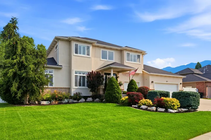 Two-story stucco residence featuring a covered entry, multiple windows with white trim, and an attached two-car garage