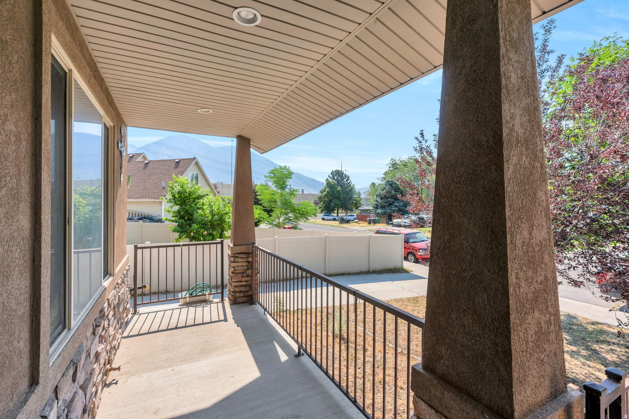 Covered porch featuring a concrete surface, black metal railing, and recessed lighting