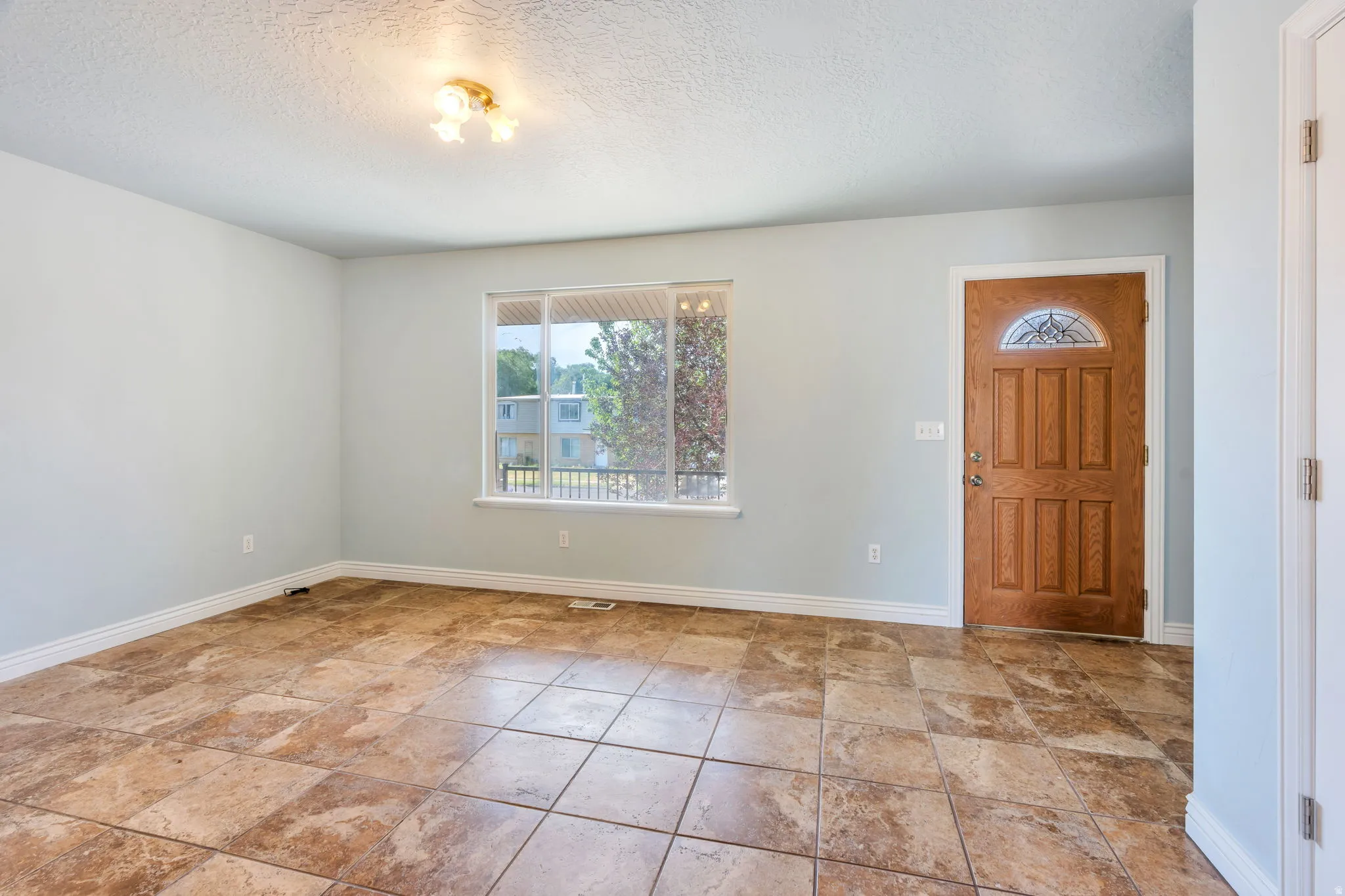Entryway featuring a paneled wood door with an arched glass insert, tiled flooring, and a large window