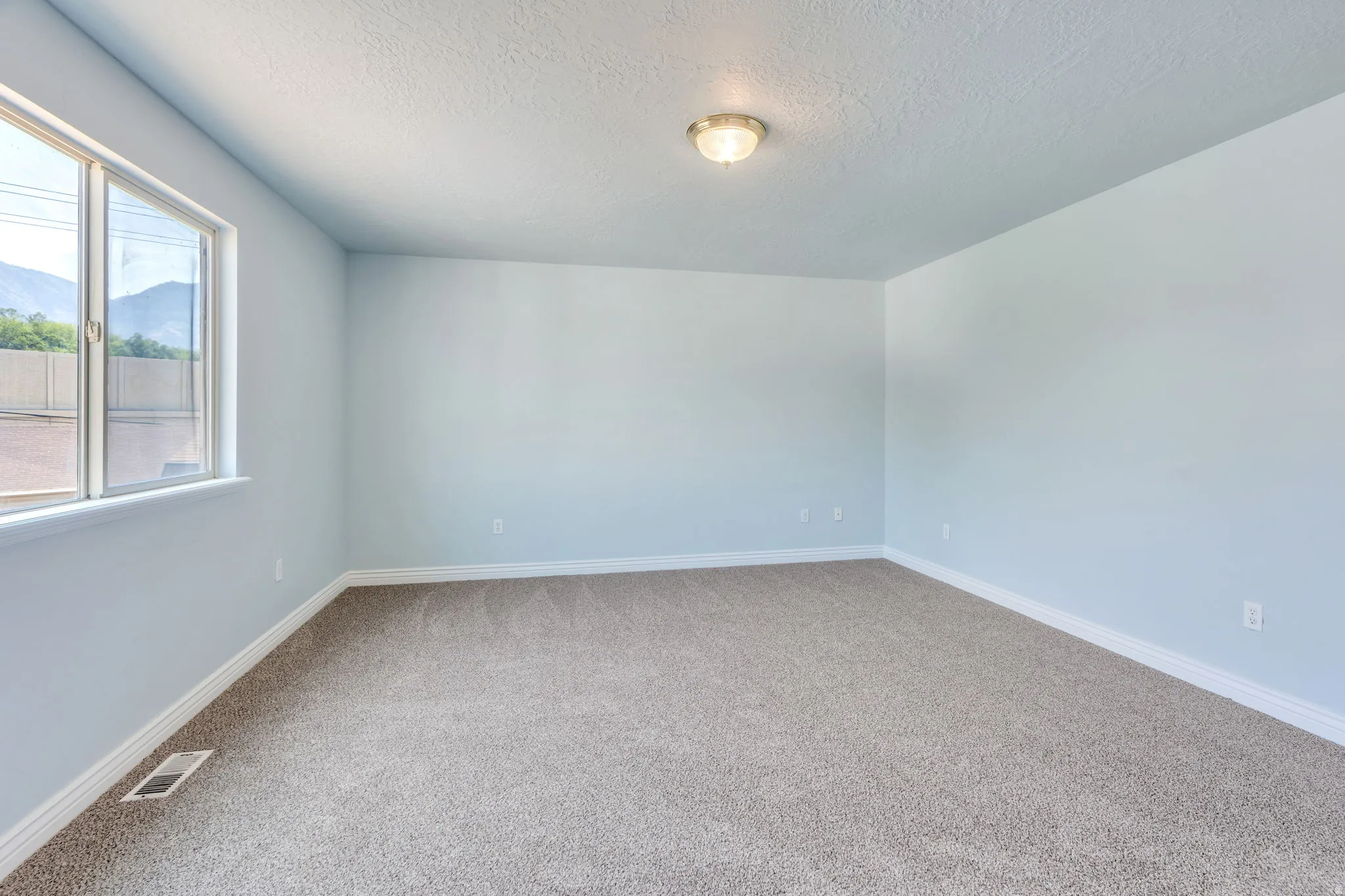 Spacious room featuring neutral carpeting, light blue wall paint, white trim, and an overhead flush mount light fixture
