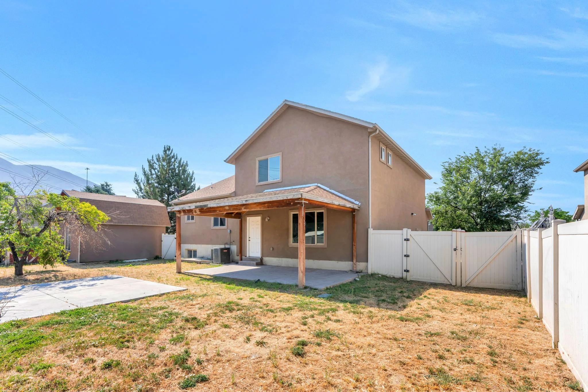 Rear exterior featuring a covered patio with exposed wood beams, a concrete slab, and a private fenced yard