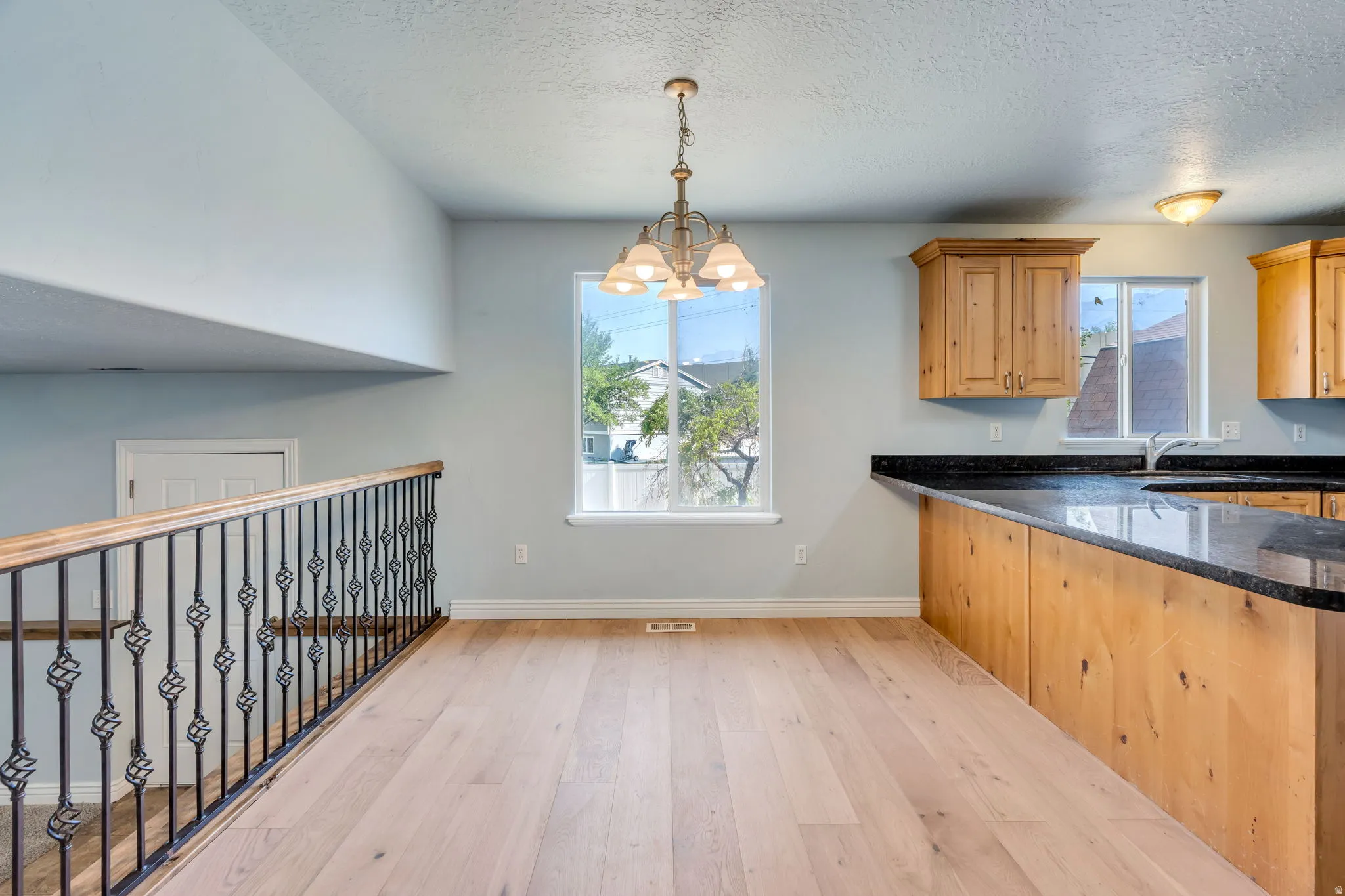 Wood-finish flooring throughout, featuring a kitchen peninsula with a dark granite countertop and light wood cabinetry