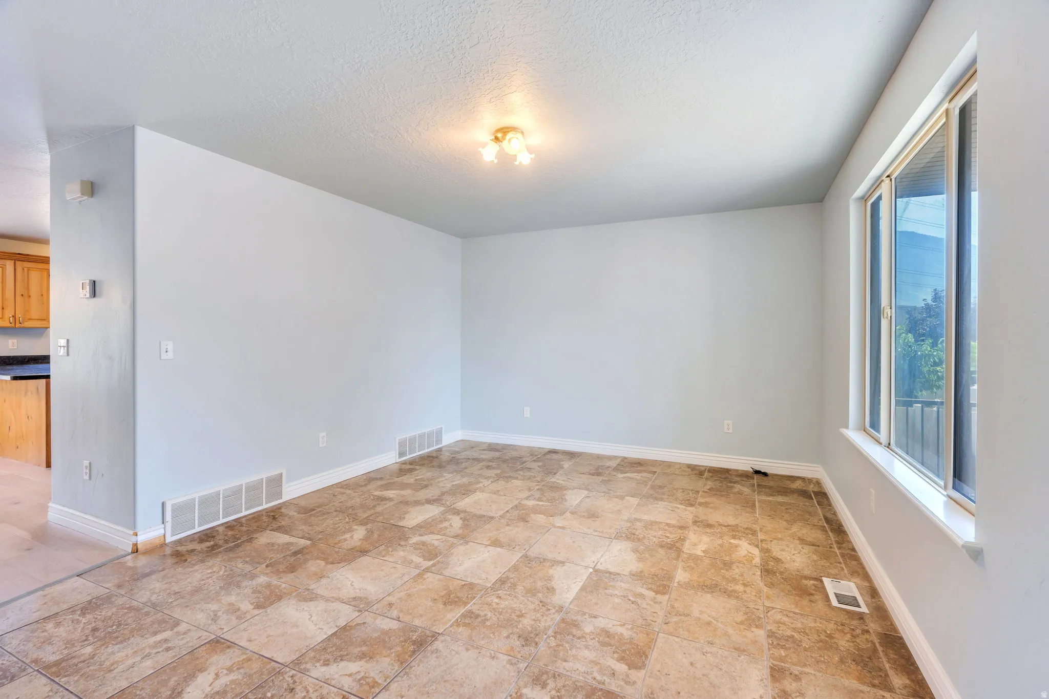 Spacious interior room featuring tile flooring, light neutral wall paint, and white baseboards
