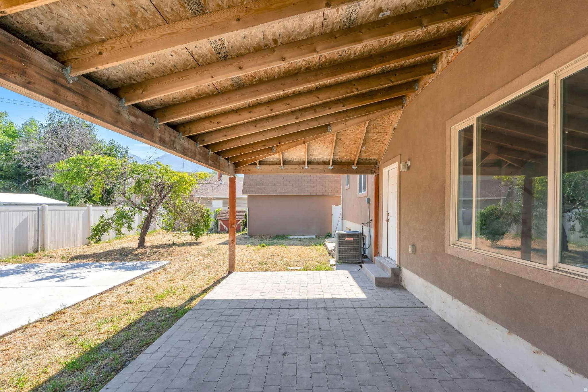 Covered patio featuring paver flooring and an exposed wood ceiling