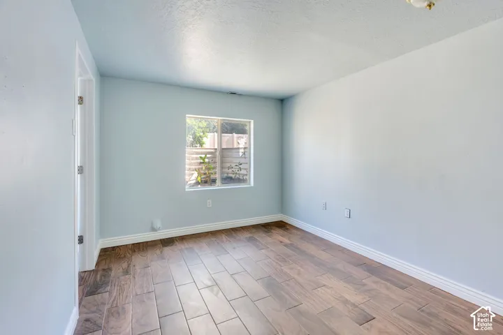 Bright room featuring wood-finish flooring, light blue wall paint, white baseboards, a single window, and a white ceiling