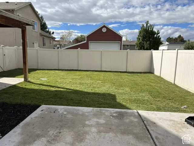 Fenced backyard featuring a manicured lawn, concrete patio, and a covered timber post structure
