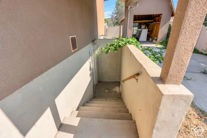 Concrete exterior stairway with a wood-finish handrail, leading to a lower-level entry