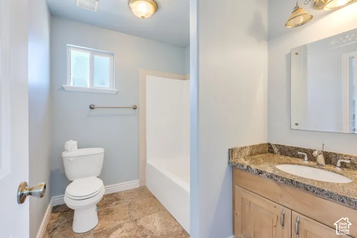 Bathroom featuring a light wood-finish vanity with granite countertop, an integrated sink, and a framed mirror