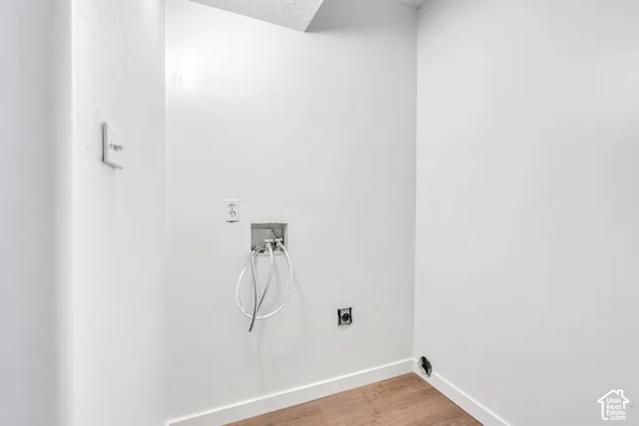 Dedicated laundry area featuring a water hookup, electrical outlet, and wood-finish flooring